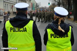 Policjantka i policjant ruchu drogowego. W tle żołnierze