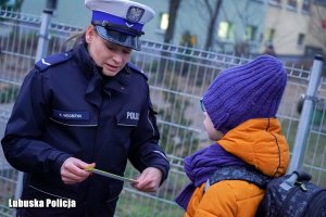 policjantka wręcza uczniowi odblaski