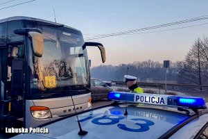 Policjant drogówki stojący przed autokarem.