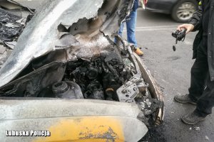 Mężczyzna z aparatem przed spalonym samochodem