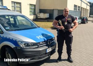 sierżant Dawid Olkiewicz na tle jednostki Policji.