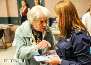 Policjantka wręcza ulotkę informacyjną.