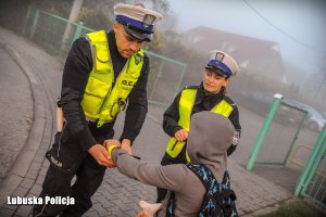 Policjant zakłada opaskę odblaskową.