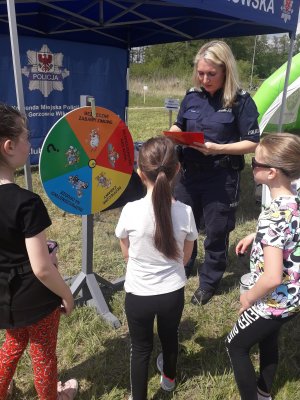 policjantka tłumaczy dzieciom na czym polega zabawa z kołem profilaktycznym