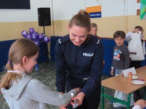 Policjantka zakłada dziecku odblask na rękę.