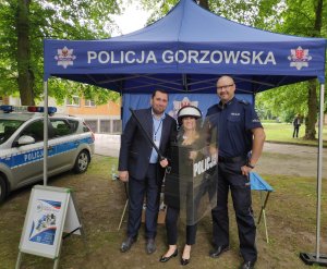 Policjant z pracownikami GCPR przymierzjącymi policyjny sprzęt taktyczny.