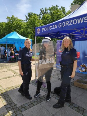 Policjantki z uczestniczką festynu, która trzyma tarczę w ręku.