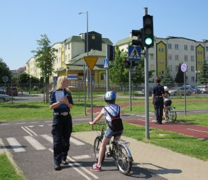 Dzieci podczas egzaminów na kartę rowerową na miasteczku ruchu drogowego pod okiem policjantek.