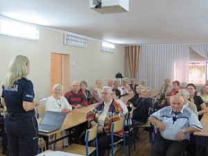 Policjantka rozmawia z seniorami.