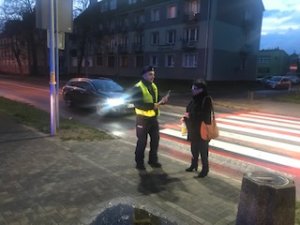 policjant wręcza pieszemu odblask