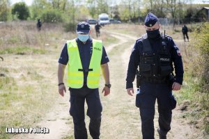 policjanci idący polną drogą