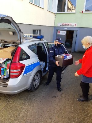 policjantka przekazuje pracownicy Caritasu paczki