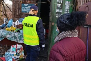 policjantka przy kontenerze, gdzie mieszkają bezdomni