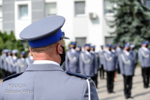 policjant obrócony tyłem, w tle awansowani funkcjonariusze