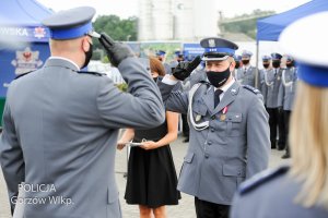 komendant i policjant oddają honory podczas wręczania aktów mianownaia