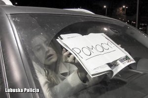kobieta w samochodzie z kartką z napisem &quot;pomocy&quot;
