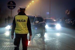 policjant z latarką, w tle auta