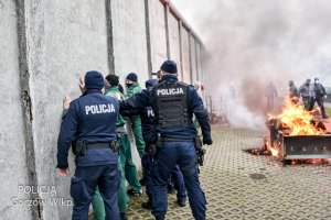 policjanci i zatrzymani przy murze