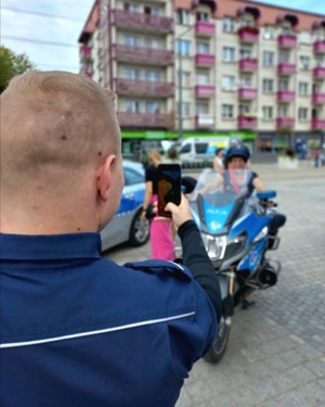 Policjant robi zdjęcie dziecku , które siedzi na motocyklu.