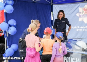 Policjantki i dzieci na stoisku profilaktycznym.