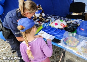 Policjantka i dziecko na stoisku profilaktycznym.