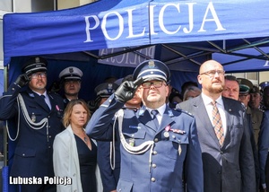 Policjant i inne osoby podczas odgrywania hymnu państwowego.