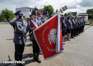 Poczet sztandarowy i policjanci podczas odgrywania hymnu państwowego.