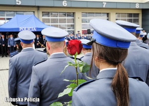 Policjantka z różą stojąca w szeregu wśród innych policjantów podczas obchodów Święta Policji.