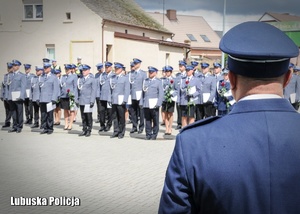 Policjant na tle pozostałych policjantów stojących w szeregu.