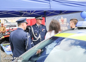 Komendanci policji na stoisku profilaktycznym rozmawiają z młodymi ludźmi.