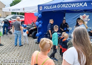 Stoisko profilaktyczne Policji, przy którym znajdują się policjantki i dzieci.