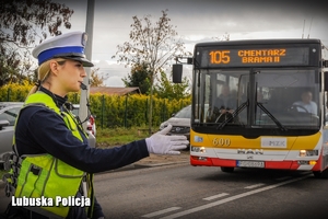 Policjantka drogówki podczas kierowania ruchem na skrzyżowaniu - w tle autobus.