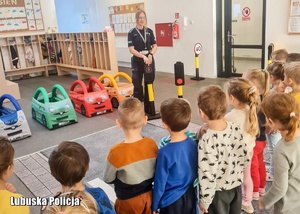 Policjantka stoi przed dziećmi i opowiada o sygnalizacji świetlnej