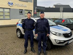 Policjanci stoją przed radiowozem