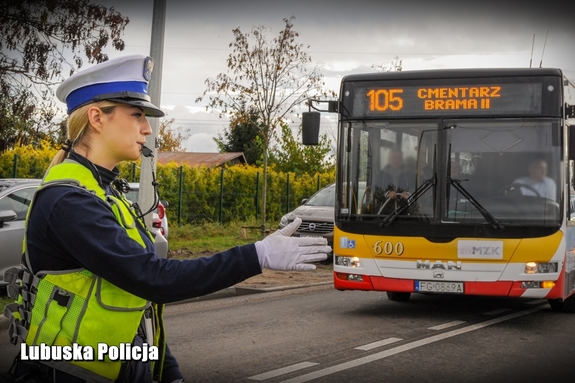 policjantka ruchu drogowego, w tle autobus jadący na cmentarz