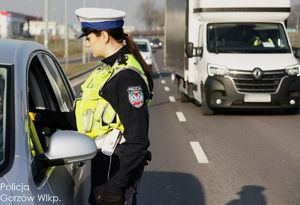 policjant ruchu drogowego na drodze bada trzeźwość kierującego pojazdem
