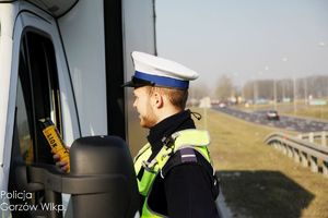 policjant ruchu drogowego na drodze bada trzeźwość kierującego pojazdem